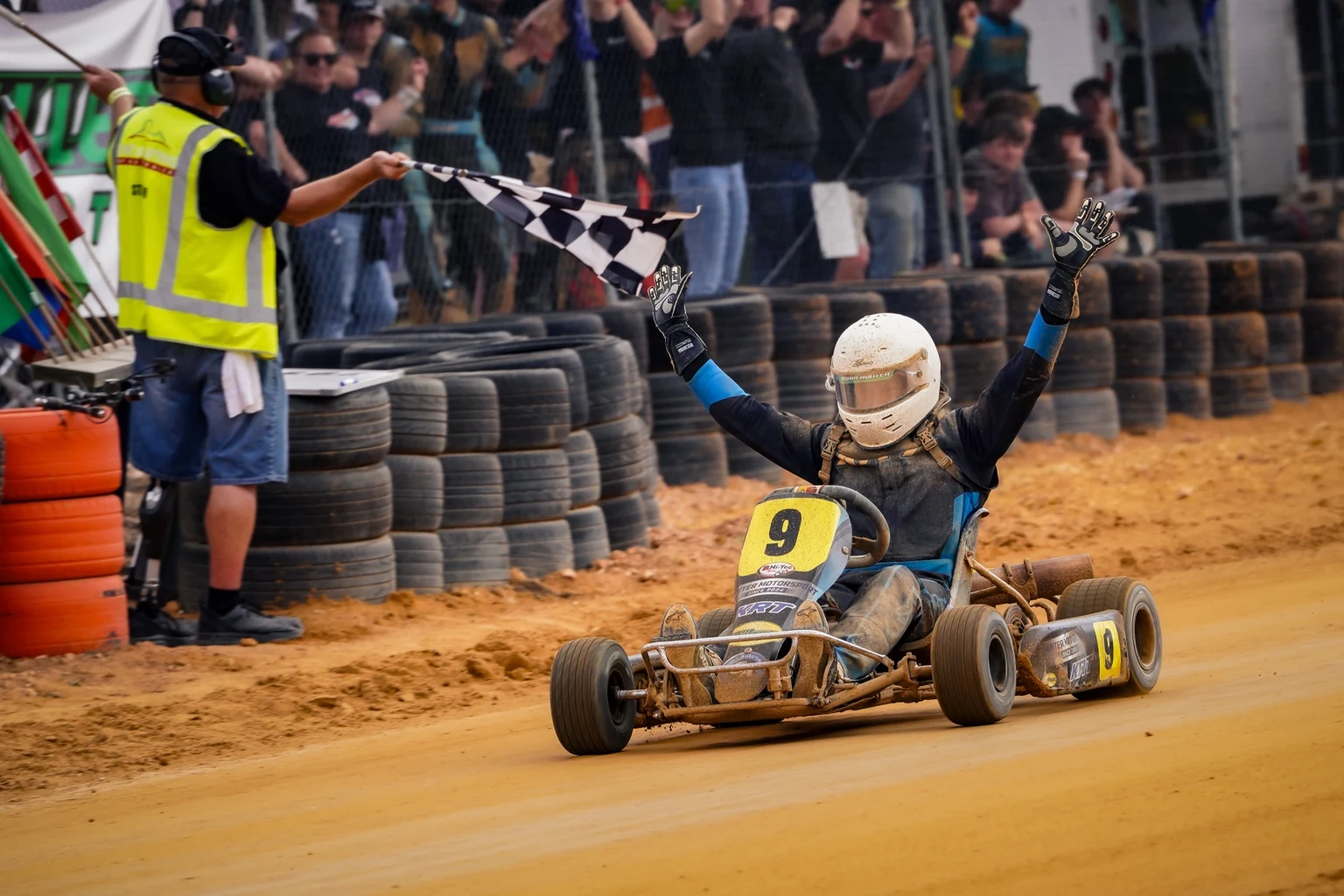 Adam Hunter celebrating in kart number 9 with arms raised after victory